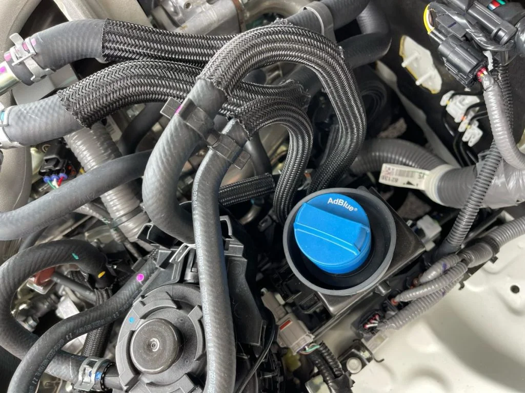 TOYOTA HILUX GUN125 アドブルータンクの青いキャップとエンジンルーム内部の配管様子