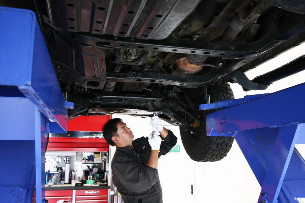 リフトで持ち上げた車両の下回りを整備するスタッフを撮影した写真