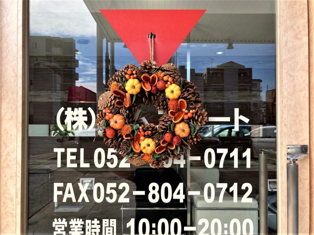 店舗ガラス扉に飾られた秋のリースを店内側から撮影した写真