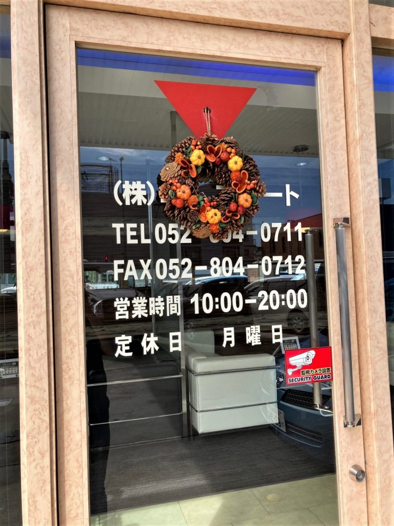 店舗の入口ドアに飾られた秋のリースを外側から撮影した写真