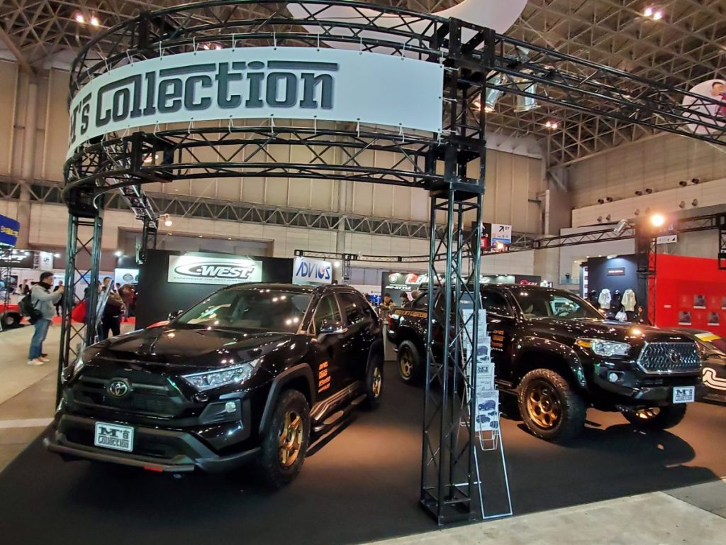 自動車ショーのM'sコレクションブースに展示された黒いカスタムSUV2台を撮影した写真
