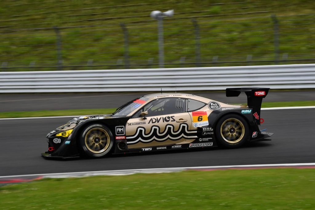 サーキットを走行するレースカーを真横から撮影した写真