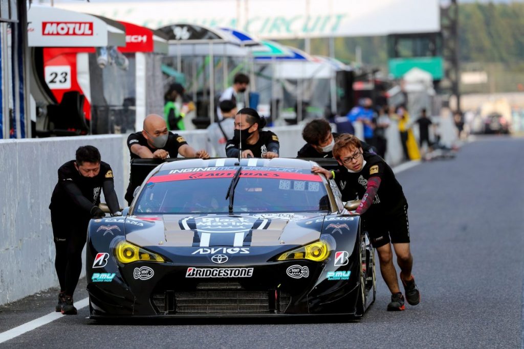 ピットでスタッフがレースカーを押して移動させる様子