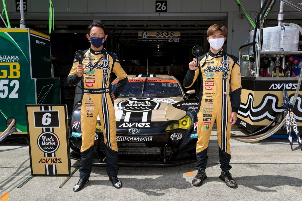 マスクをつけたドライバー2名がレースカーの前で記念撮影する様子