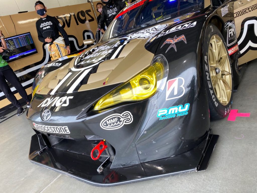 金色のホイールを履いたスーパーGTマシンのフロント部分をピットで撮影した写真