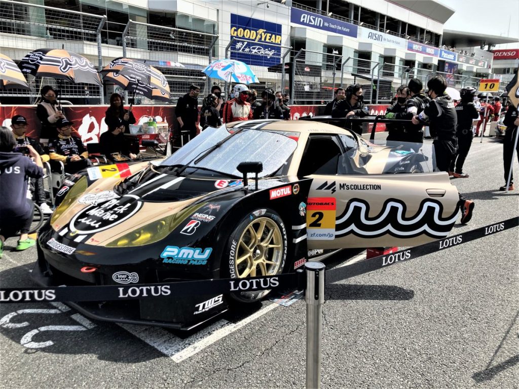 ピットレーンに停められたレースカーの側面と観客の様子