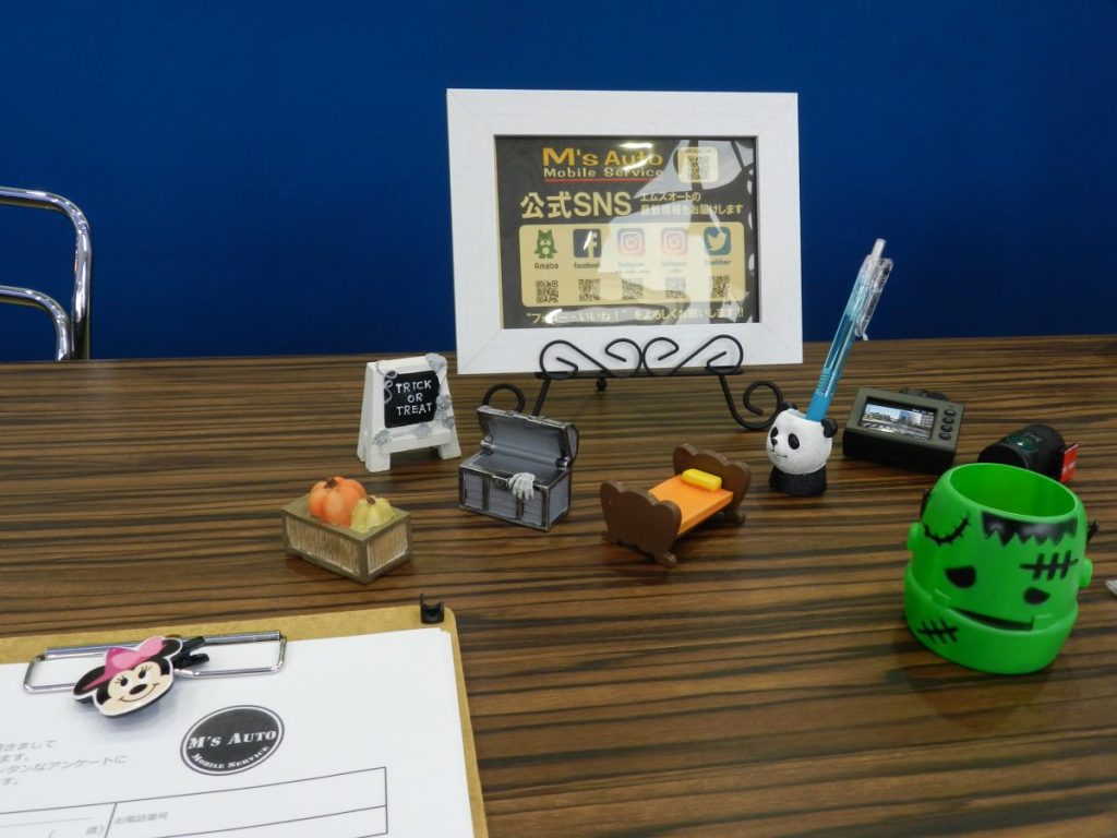 エムズオート店内 受付デスクのカボチャ飾りとSNS案内ボード